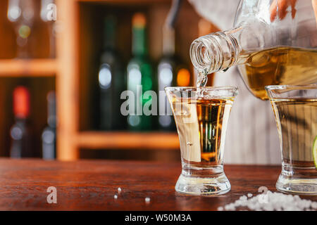Barman pouring savoureuse bouteille de tequila dans un verre sur le comptoir Banque D'Images