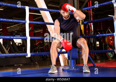 Sporty man sitting in coin de ring de boxe Banque D'Images