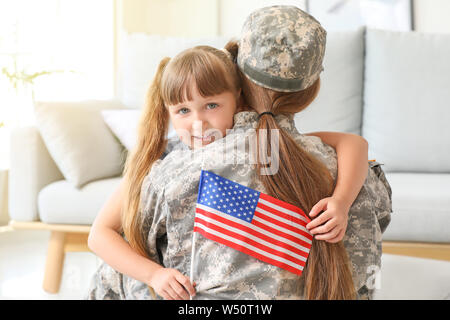 Heureux femme soldat de l'armée USA étreindre sa petite fille à la maison Banque D'Images