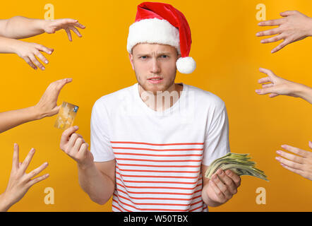 Les mains de jeune homme a souligné in Santa hat, avec carte de crédit et de l'argent sur un fond de couleur Banque D'Images