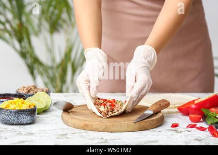 Femme préparant de délicieux tacos frais dans la cuisine Banque D'Images