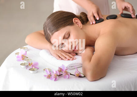 Belle jeune femme en traitement aux pierres chaudes au spa salon Banque D'Images