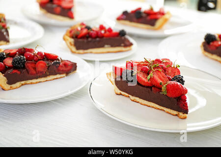 Les plaques avec des morceaux de chocolat délicieux gâteau aux fraises sur tableau blanc Banque D'Images