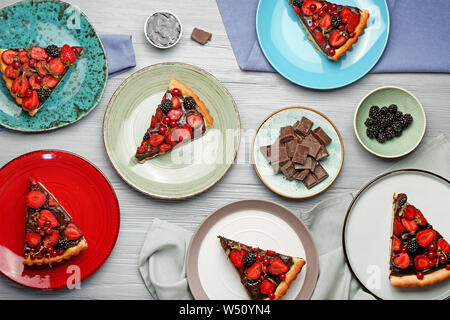 Les plaques avec des morceaux de chocolat délicieux gâteau aux fraises sur table en bois Banque D'Images