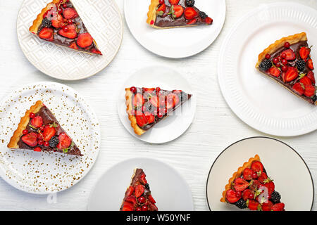 Les plaques avec des morceaux de chocolat délicieux gâteau aux fraises sur tableau blanc Banque D'Images