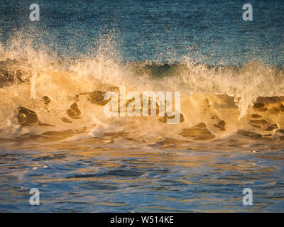 Matériel roulant dans les vagues de la plage avec l'après-midi du soleil brillant à travers Banque D'Images
