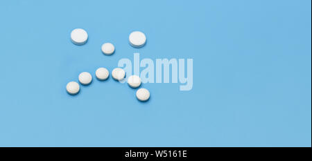 Bannière. Visage triste de comprimés ronds blancs sur fond bleu. Place sous l'inscription publicité Banque D'Images