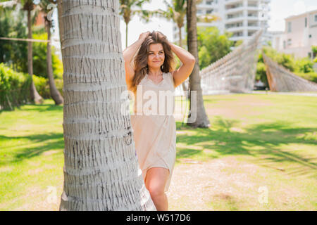 Happy young woman standing sous les palmiers aux beaux jours de vacances en Thaïlande holding sa jolie cheveux avec les mains Banque D'Images