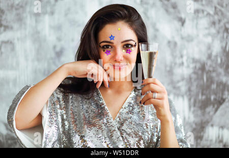 Portrait de la jeune femme avec des composent le port de tenue de cocktail holding glass of champagne Banque D'Images