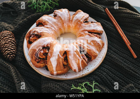 Bague plateau suédois gâteau de Noël à la cannelle, les pacanes et les raisins secs sur une chaude chandail tricoté. Le concept d'ambiance vacances d'hiver et de boulangerie. Banque D'Images