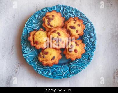 Délicieuses madeleines aux raisins servi sur une assiette bleue, vue du dessus Banque D'Images