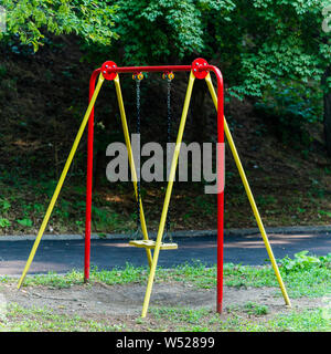 Balançoires pour enfants accrocher un vide au ralenti à une aire de jeux sur un jour nuageux, terne. Banque D'Images