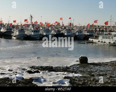 Une vue sur les bateaux de pêche ancrés sur la surface de la mer congelés dans un port après de fortes smog dans Tianjin, Chine, 15 janvier 2019. Banque D'Images
