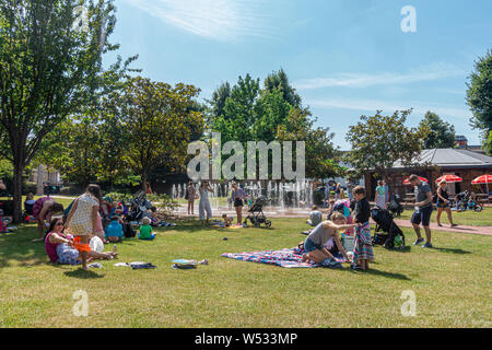 Les jeunes familles se détendre dans un parc, Acre célibataires à Windsor, Royaume-uni sur une chaude journée d'été ensoleillée. Banque D'Images