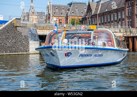 Les touristes de prendre une excursion en bateau sur le canal de nombreux canaux autour de la ville néerlandaise d'Amsterdam. Banque D'Images