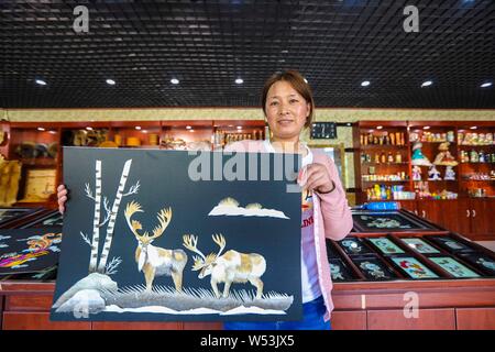 Une femme chinoise des Hezhen Personnes montre une peinture faite de peaux de poisson dans un magasin du comté de Raohe, Shuangyashan city, au nord-est de l'Anhui en Chine Banque D'Images