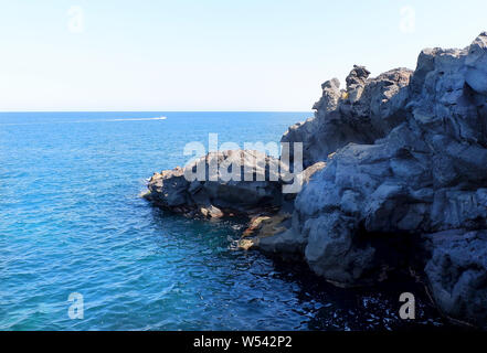 Les falaises volcaniques noires au bord de la mer Méditerranée en Italie. Catane, Sicile. Banque D'Images