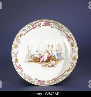 Assiette, tasse et soucoupe soucoupe-assiette avec une image symbolique de Trois putti et différents objets, plat en porcelaine peinte sur l'émail en bleu, rouge, rose, vert, jaune, marron, noir et or. Sur l'étagère du plat une représentation symbolique avec trois putti, l'un des qui souffle des bulles de savon dans un tuyau, derrière eux un panier en osier, pyramide, skull, masque, couronne, globe, livres et autres objets, la frontière avec une bande de feuilles de vignes, des rubans, des branches et des deux soleils avec un visage radieux. Présentation d'après un dessin de Jacob de Wit (1695-1754), 'Allégorie de l'errance". Le mur a été cassé. European Banque D'Images