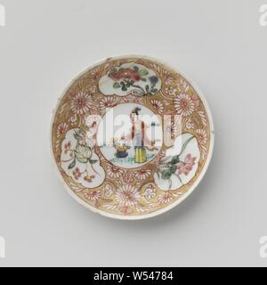 Soucoupe d'une dame avec panier de fleurs et de plantes à fleurs dans les panneaux, plat en porcelaine avec diffusion, mur peint sur l'émail en bleu, rouge, rose, vert, noir et or. Sur la plaque du plat un médaillon avec une dame dans un paysage avec un panier de fleurs, de fleurs de vignes qui ont été enregistrés dans le médaillon et trois cartouches avec des plantes à fleurs (y compris lotus) dans la masse d'or. Plat a été brisée. Famille rose., anonyme, la Chine, l'c. 1725 - c. 1749, dynastie Qing-(1644-1912) / Yongzheng-période (1723-1735) / période de Qianlong (1736-1795), Porcelaine, glaçure (matériel), de l'or (métal Banque D'Images