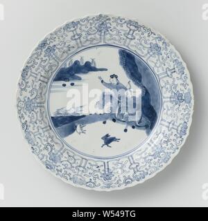 Saucer dish avec scène de chasse, lotus morte et les symboles auspicieux, plat en porcelaine avec paroi côtelée, rond et bord cannelé, peint en bleu sous glaçure. Sur la télévision d'une scène de chasse avec deux cavaliers armés dans un paysage, la chasse un lièvre, la frontière avec une bande de vrilles lotus concaténés, entre lesquels les huit symboles de bonheur (chakra, shell, parasol, auvent, lotus, vase, poisson, nœud infini), l'arrière avec 16 sprays de fleurs distinctes. Marqué sur le dessous avec la marque à six caractères de l'empereur dans un double cercle Xinian Square. Edge légèrement endommagé. Bleu Blanc., anonyme, de la Chine, c Banque D'Images