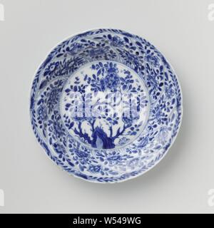 Saucer avec panneaux torsadés et sprays de fleurs, plat en porcelaine avec paroi ronde modélisé dans dix boîtes torsadée, peint en bleu sous glaçure. Sur la télévision un rocher avec une fleur, une fleur branche sur le mur dans chaque compartiment, la frontière avec une fleur de vigne, à l'arrière aussi une fleur branche dans chaque compartiment. Inscrite sur le fond avec le caractère chinois "Fú' dans un double cercle. Bleu Blanc., Fú', anonyme, la Chine, l'c. 1680 - c. 1720, Qing Dynasty, Kangxi (1644-1912) / (1662-1722) période, Porcelaine, glaçure (matériel), le cobalt (minéral), la vitrification, H 2,5 cm d 13,6 cm d 7 cm Banque D'Images