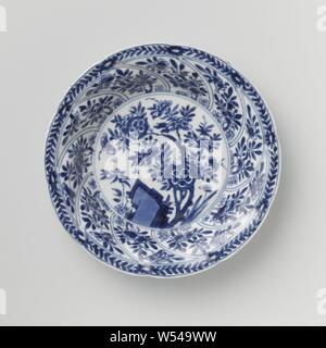 Saucer avec panneaux torsadés et sprays de fleurs, Porcelaine soucoupe sur mur rond modélisé dans dix boîtes torsadée, peint en bleu sous glaçure. Sur la télévision un rocher avec une branche de fleurs et de plantes, d'une fleur branche sur le mur dans chaque compartiment, la frontière avec une fleur de vigne, à l'arrière aussi une fleur branche dans chaque compartiment. Inscrite sur le fond avec le caractère chinois "Fú' dans un double cercle. Une puce et d'une fissure dans le bord. Bleu Blanc., Fú', anonyme, la Chine, l'c. 1680 - c. 1720, Qing Dynasty, Kangxi (1644-1912) / (1662-1722) période, Porcelaine, glaçure (matériel), le cobalt (minéral), la vitrification Banque D'Images