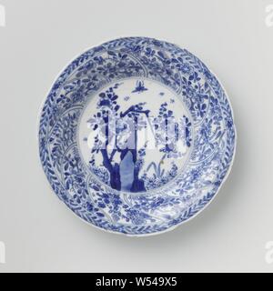 Saucer avec panneaux torsadés et sprays de fleurs, plat en porcelaine avec paroi ronde modélisé dans dix boîtes torsadée, peint en bleu sous glaçure. Sur la télévision un rocher avec une branche de fleurs, de plantes et de papillons, une fleur branche sur le mur dans chaque compartiment, la frontière avec une fleur de vigne, à l'arrière aussi une fleur branche dans chaque compartiment. Inscrite sur le fond avec le caractère chinois "Fú' dans un double cercle. Quelques jetons dans le bord. Bleu Blanc., Fú', anonyme, la Chine, l'c. 1680 - c. 1720, Qing Dynasty, Kangxi (1644-1912) / (1662-1722) période, Porcelaine, glaçure (matériel), le cobalt (minéral), la vitrification Banque D'Images