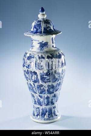 Vase balustre couvert avec des paysages dans les panneaux en forme de balustre, vase en porcelaine, peint en bleu sous glaçure. L'abdomen est divisé en cinq rangées de feuilles de lotus en forme de cartouches avec les paysages. Un paysage continu sur le cou. Le couvercle en forme de cloche est divisé en six compartiments avec les paysages. Au-dessus du pied, sur l'épaule, la jante et le couvercle d'une jante avec une bande motif en zigzag. Quelques jetons dans le bord du couvercle. Couvercle vase est partie d'un ensemble de l'armoire. Bleu Blanc., anonyme, la Chine, l'c. 1700, Qing Dynasty, Kangxi (1644-1912) / (1662-1722) période, Porcelaine, glaçure (matériel), le cobalt (minéral Banque D'Images