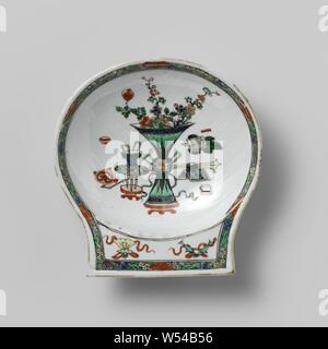 En forme de coquille de pétoncle bol avec antiquités, Bol en porcelaine en forme de coquillage, côtelées, mur peint sur l'émail en bleu, rouge, vert, jaune, aubergine, noir et or. Sur le fond d'antiquité (vase à fleurs, un sceptre ruyi, encens, etc.), sur la poignée de la chance deux symboles (parasol, poissons), en bordure des vignes de lotus stylisé sur un fond vert moucheté noir. Leurs vitres arrière. Puce dans le bord. Famille verte., anonyme, la Chine, l'c. 1700 - c. 1724, Qing Dynasty, Kangxi (1644-1912) / (1662-1722) Période / Yongzheng-période (1723-1735), Porcelaine, glaçure (matériel), le cobalt (minéral), de l'or (métal Banque D'Images