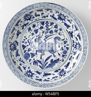 Chargeur avec un plat avec un qilin qilin près d'un rocher parmi les plantes, grand plat en porcelaine, décor peint en bleu. Sur l'étagère dans un médaillon d'un qilin en flammes à proximité d'un rocher, entouré de plantes à fruits (raisin, banane, melon). La paroi interne avec lotus la vigne. Sur le bord intérieur d'une serviette avec bande de travail. Avec une bande morte sur le mur extérieur. Deux fissures dans le bord. Le fond est non. Yuan en porcelaine bleu et blanc, encore d'autres animaux fabuleux qui ne peuvent être classés dans 25 FF 2 25 FF - 7 ornement, dérivés de formes végétales, anonyme, la Chine, l'c. 1350, Yuan-dynastie (1279 Banque D'Images