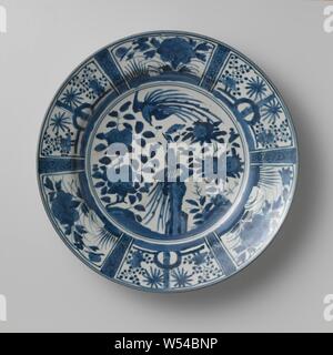 Plat avec deux hoo-oiseaux près des rochers et des plantes à fleurs, plat en porcelaine, décor peint en bleu. Sur un médaillon d'un oiseau de foin sur un rocher avec des plantes à fleurs (pivoines, grenade). Un deuxième oiseau vole au-dessus. La frontière est divisé en compartiments larges et étroites. Les boîtes de large avec des plantes à fleurs (pivoines, prunus, Camellia) à proximité de rochers, les boîtes étroites avec une branche de fleurs. Cinq proen sur le fond. La décoration est basée sur les Chinois kraak porcelaine. Bleu Blanc., anonyme, le Japon, l'c. 1650, période Edo (1600-1868), Porcelaine, glaçure (matériel), le cobalt (minéral), la vitrification, h 5. Banque D'Images