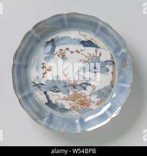 Plat de soucoupe avec des plantes à fleurs et rochers, plat en porcelaine avec le mur modélisé sous la forme de pétales et bordure lobée, peint en bleu sous glaçure et sur l'émail rouge et or. Sur la télévision des plantes à fleurs (prunus) et de pivoine, de roches et de nuages. Le mur est recouvert de bleu avec trois branches de fleurs en or sur l'émail. L'extérieur du mur est également couverte de bleu. Cinq proen sur le fond. Sur le dessous la marque à six caractères de l'empereur. Xinian Square Imari., anonyme, le Japon, l'c. 1675 - c. 1725, période Edo (1600-1868), Porcelaine, glaçure (matériel), le cobalt (minéral), de l'or (métal Banque D'Images