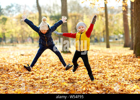 Des enfants heureux tournant au autumn park Banque D'Images