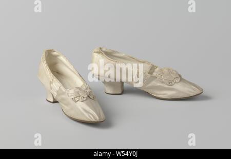 Des chaussures en satin blanc ivoire avec noeud avec boucles multiples et au milieu des perles de verre, des chaussures en satin blanc ivoire. Modèle : Le nez est rond, un avant et un arrière. L'avant du talon va droit vers le bas. Les côtés et l'arrière du talon sont montés et recouverts de satin blanc ivoire. Le talon a une jante en cuir brun foncé de l'arrière. Retour en cuir avec huit ongles lié au talon et semelle en cuir. Couverture arrière bordée de cuir blanc ivoire, couverture bordée de lin. La semelle intérieure est en cuir blanc ivoire. Décoration : au centre devant l'ouverture de la chaussure avant Banque D'Images