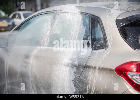 Voiture à l'aide de nettoyage de l'eau sous pression à l'extérieur. Voiture moderne couverte par l'eau. Vue arrière de voiture. Banque D'Images