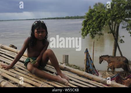 Le 26 juillet 2019, Kurigram, Bangladesh : une fille réagit à la caméra comme elle s'assoit sur une carte près de la rive de la rivière Dharla River. Selon le rapport, l'eau qui coule de la rivière Dharla 73 centimètres au-dessus du niveau de danger près de Kurigram. (Crédit Image : © MD Mehedi Hasan/Zuma sur le fil) Banque D'Images