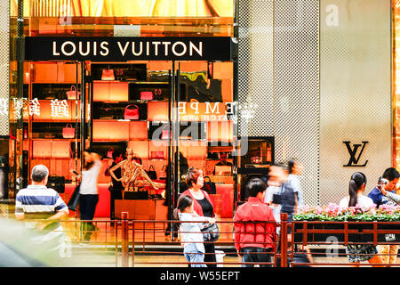 --FILE--piétons devant une boutique de mode de Louis Vuitton (LV) à Hong Kong, Chine, 5 novembre 2015. L'appétit des consommateurs riches chinois pour lu Banque D'Images