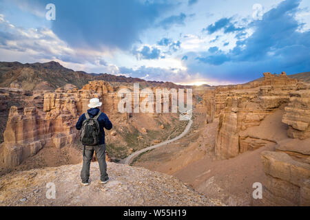 Touriste avec un sac à dos à la recherche sur le coucher du soleil à Canyon Auezov, région d'Almaty, Kazakhstan Banque D'Images