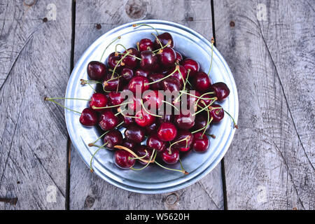 Cerises, vue de dessus les cerises mûres rouges récoltés sur table en bois et de la plaque Banque D'Images