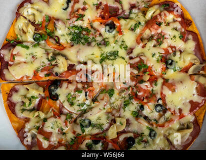 Pizza chasse avec saucisse, boeuf, tomates et olives sur la table. Banque D'Images