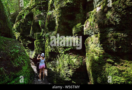 Eisenach, Allemagne. 26 juillet, 2019. Une jeune femme prend une photo dans la gorge du Dragon. L'Drachenschlucht est d'environ 2,6 kilomètres de long et a été rendu accessible en 1832. Crédit : Martin Schutt/dpa-Zentralbild/dpa/Alamy Live News Banque D'Images