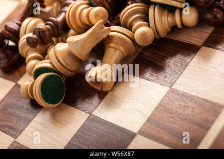 Pièces des échecs éparpillés sur un échiquier en bois close up Banque D'Images