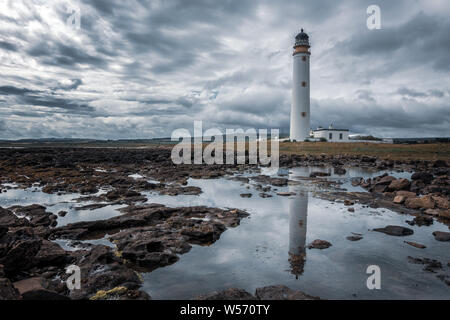 UK : Paysages image créative de Barns Ness Phare reflète dans une roche chauffée avec ciel dramatique, East Lothian, Scotland Banque D'Images