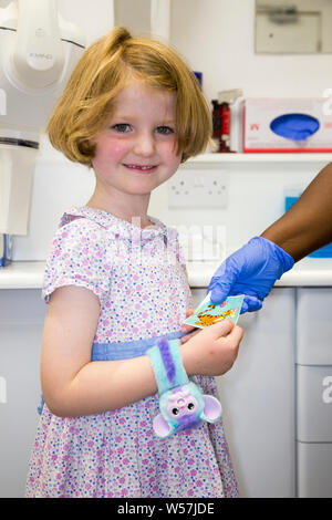 Un dentiste NHS / infirmière dentaire portant un gant en latex bleu donne un autocollant pour une fille / enfant / enfant comme une récompense à la fin d'un bilan dentaire rendez-vous. Royaume-uni (111) Banque D'Images
