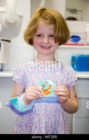 Un patient NHS / fille / jeune enfant kid reçoit un autocollant comme une récompense à la fin d'un check up dentaire heureux. Royaume-uni (111) Banque D'Images