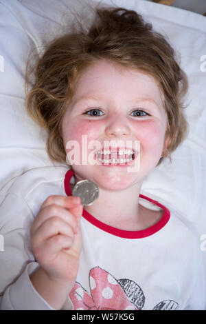 Young Girl smiling pour révéler une dent avant manquant / dents Dent, tout en maintenant un 50p / cinquante pence pièce dans laquelle sont arrivés de la fée de dent sous son oreiller. Royaume-uni (111) Banque D'Images