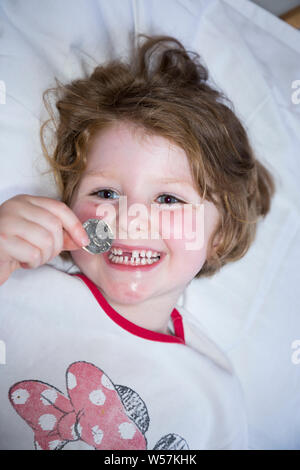 Young Girl smiling pour révéler une dent avant manquant / dents Dent, tout en maintenant un 50p / cinquante pence pièce dans laquelle sont arrivés de la fée de dent sous son oreiller. Royaume-uni (111) Banque D'Images