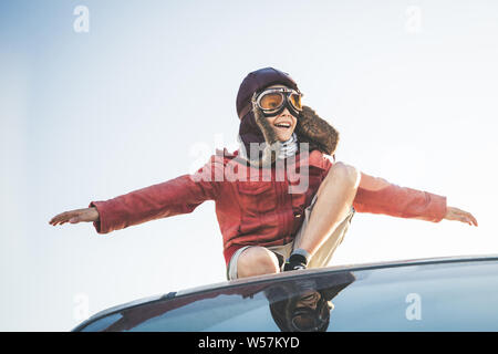 Beau garçon blond joue heureux et joyeux faisant semblant d'enlever son vol déguisé comme un pilote d'aviation vintage avec chapeau, veste en cuir eyew jaune Banque D'Images