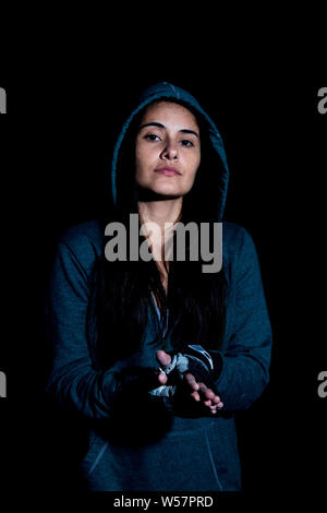 Portrait de jeune femme de mettre des gants dans le gymnase avec des gants sur fond noir Banque D'Images