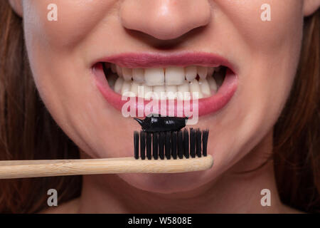 Close-up of Young Woman Holding brosse à dents avec dentifrice noir charbon actif Banque D'Images